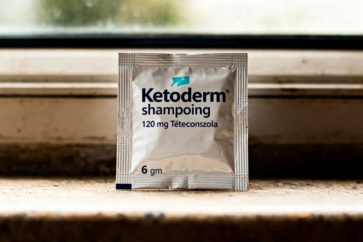 Sachet de shampooing Ketoderm 120 mg Tétéconzola, 6 gm, posé devant une fenêtre.